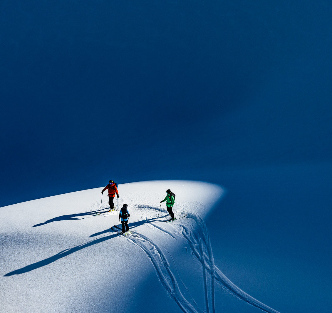 Three people standing together in the snow.